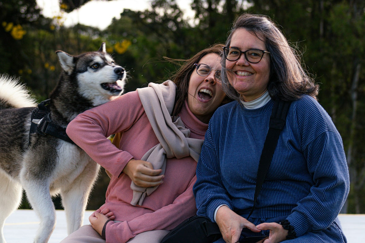 Two women outdoors with their friendly Siberian Husky, ready for a fall walk